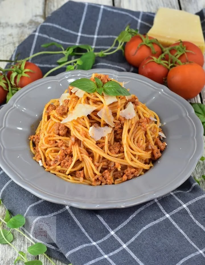 Farfurie cu paste bolognese garnisite cu busuioc proaspăt